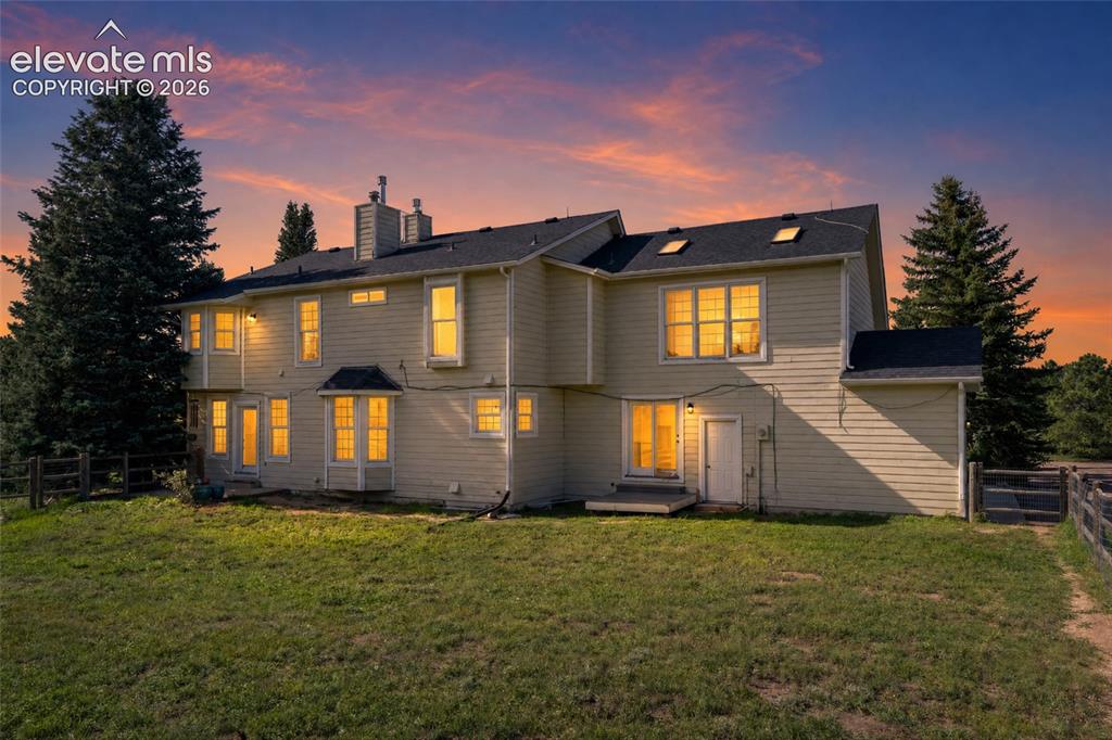 Image 46 of 49: Rear exterior featuring multiple windows, skylights, and a wood fence