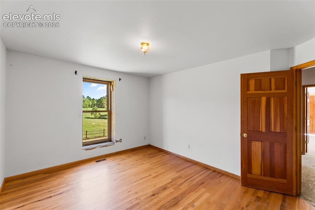 Image 49 of 49: Hardwood flooring, painted white walls, wood panel interior door, and a sin