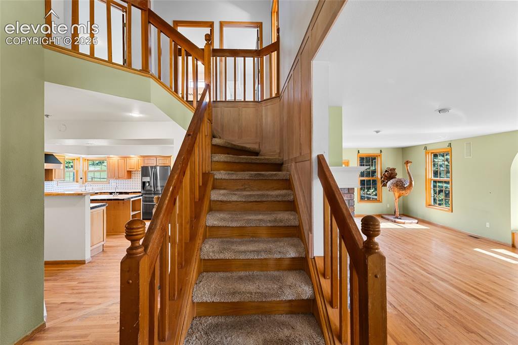 Image 5 of 49: Staircase with wood balusters and carpeted treads, wood-finish flooring, an