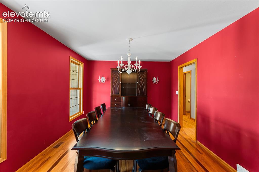 Image 9 of 49: Hardwood flooring, wood trim, built-in display cabinetry, and a chandelier