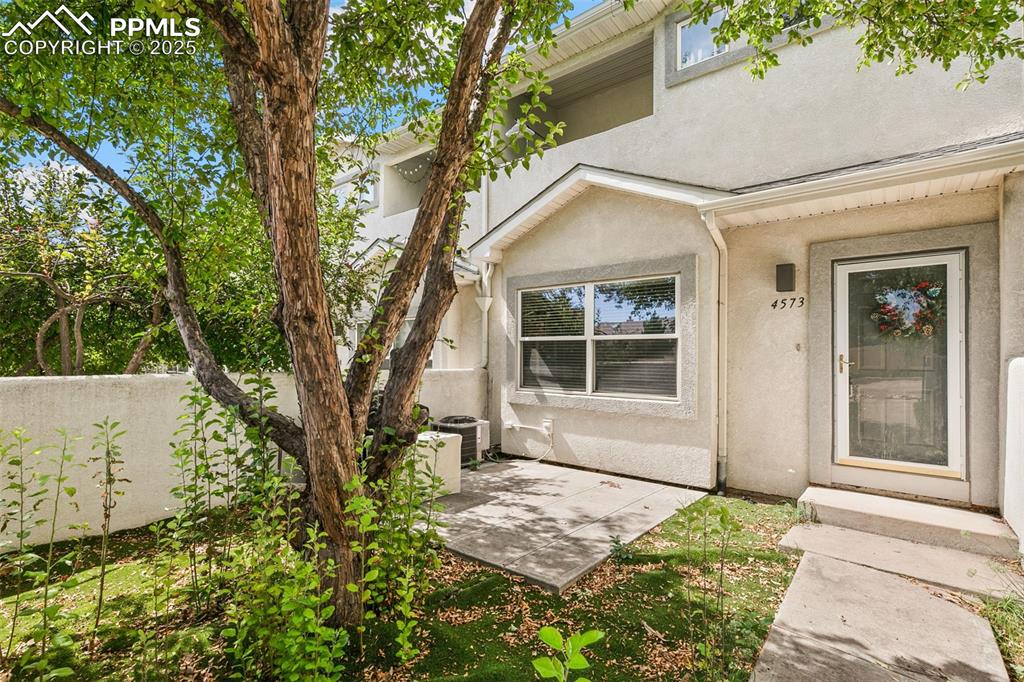 Caption: Entrance to property featuring stucco siding and a patio area