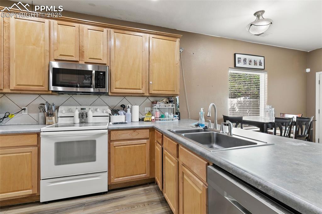 Image 12 of 29: Kitchen featuring stainless steel appliances, light countertops, backsplash