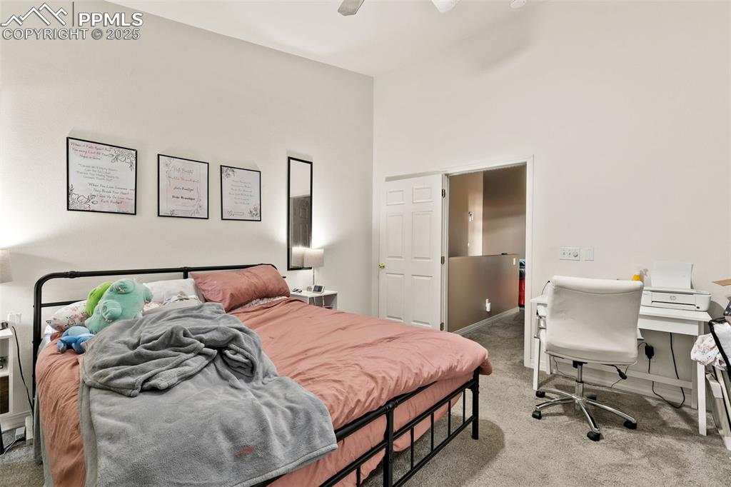 Image 18 of 29: Bedroom featuring light carpet, ceiling fan, a desk, and a high ceiling