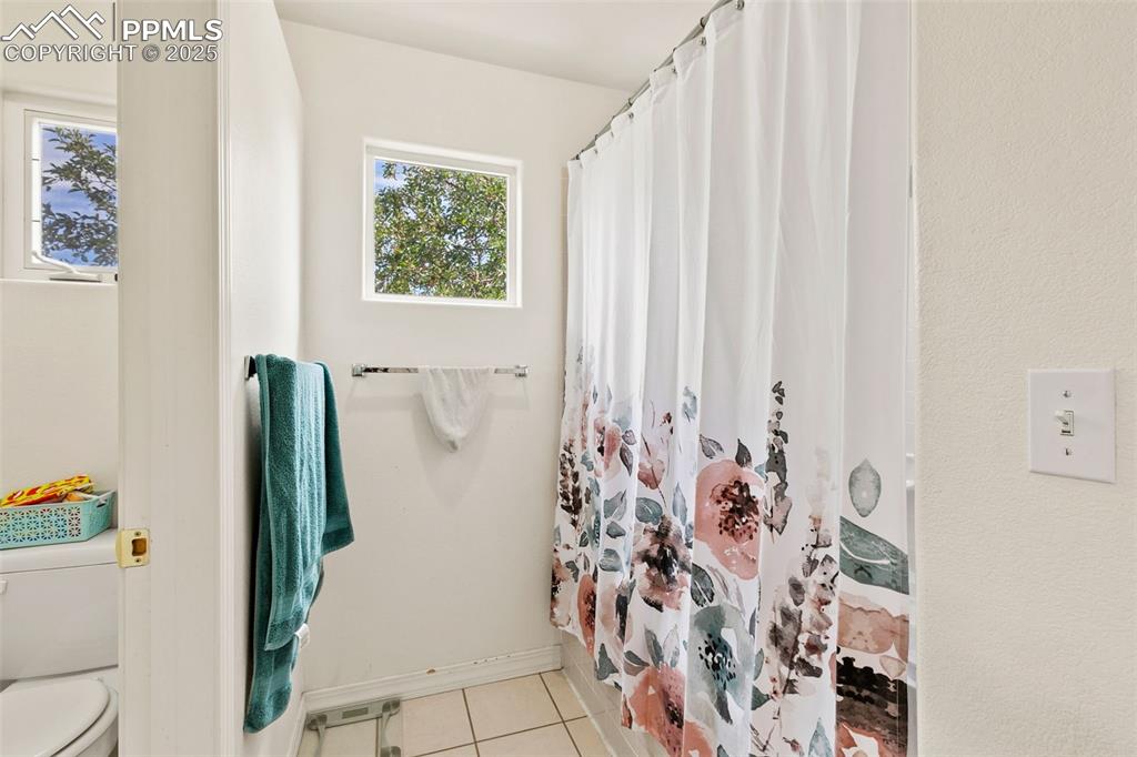 Image 20 of 29: Full bathroom featuring light tile patterned floors and curtained shower