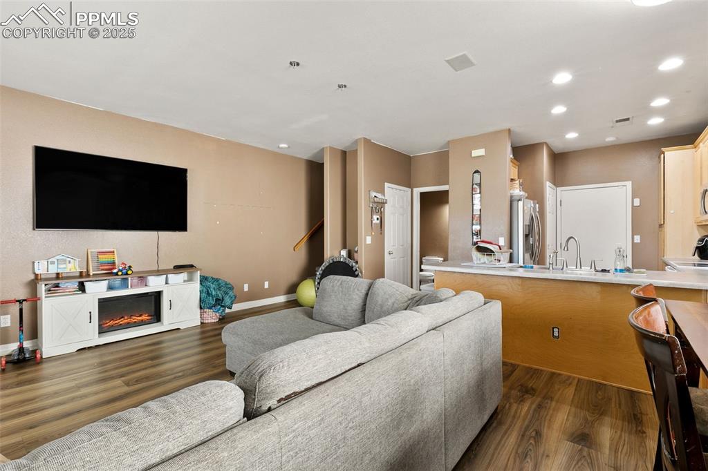 Image 4 of 29: Living area featuring dark wood finished floors, a glass covered fireplace,