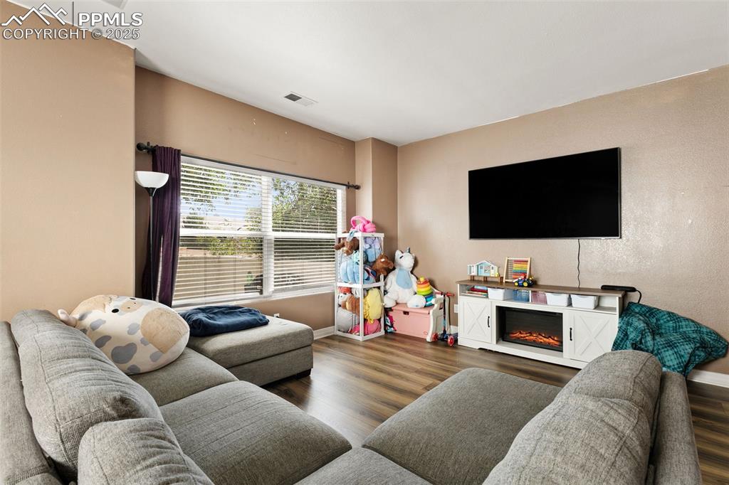 Image 7 of 29: Living area featuring dark wood finished floors and a glass covered firepla