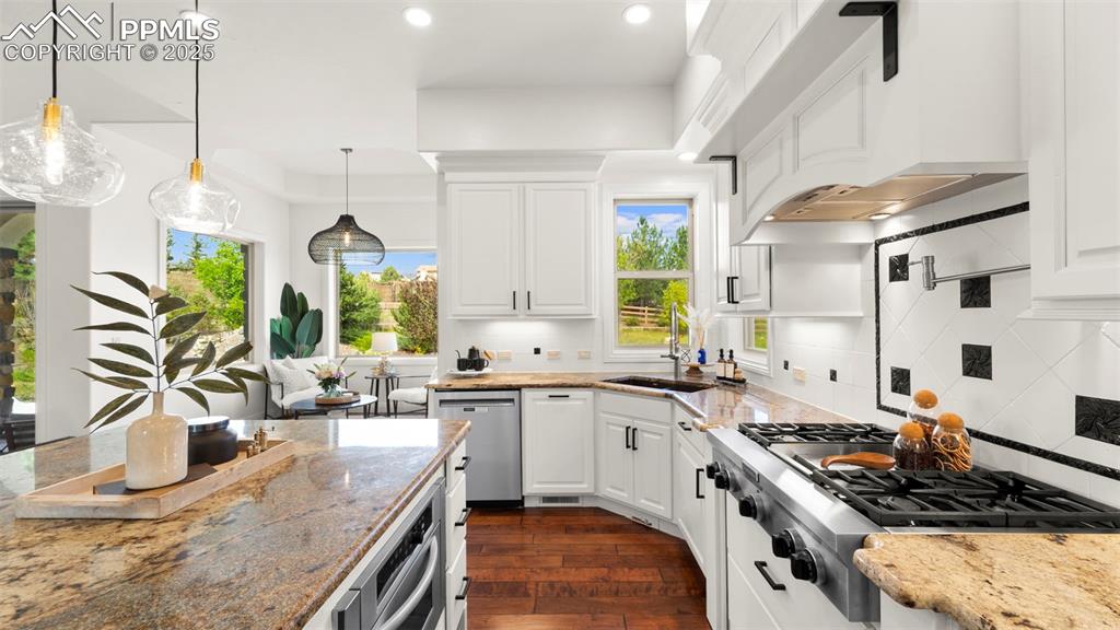 Image 12 of 50: Kitchen featuring light stone counters, appliances with stainless steel fin