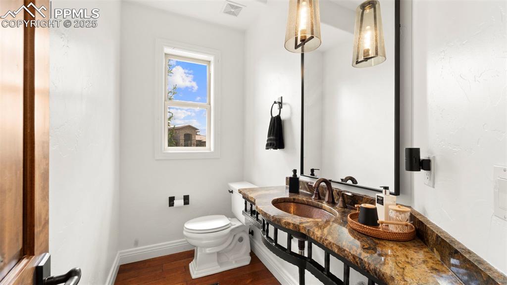 Image 16 of 50: Half bath with dark wood-style floors and vanity