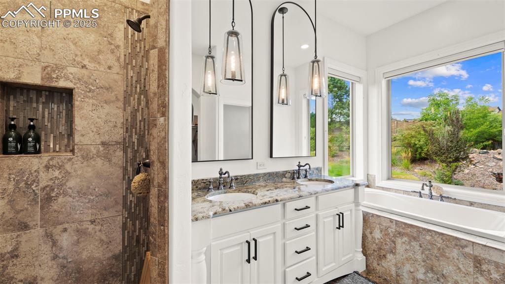 Image 20 of 50: Full bathroom featuring walk in shower, a bath, and double vanity