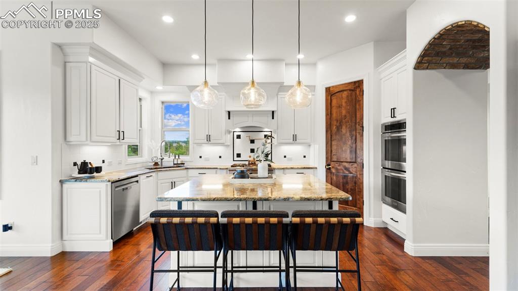 Image 21 of 50: Kitchen with a kitchen island, a kitchen bar, decorative light fixtures, li