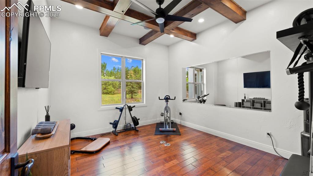 Image 23 of 50: Exercise area with hardwood / wood-style floors, a ceiling fan, and coffere