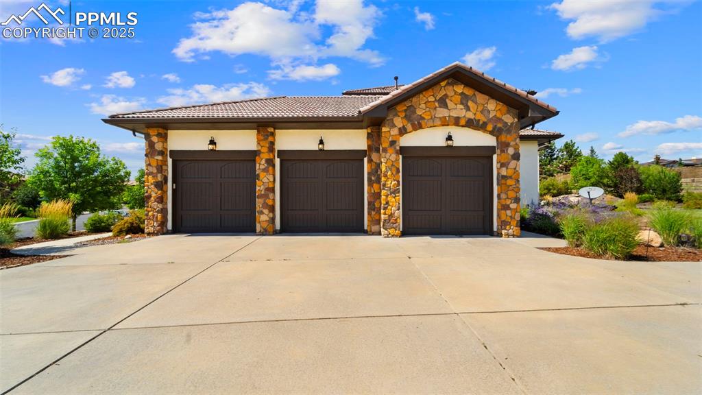 Image 39 of 50: Mediterranean / spanish home with concrete driveway, stone siding, a garage
