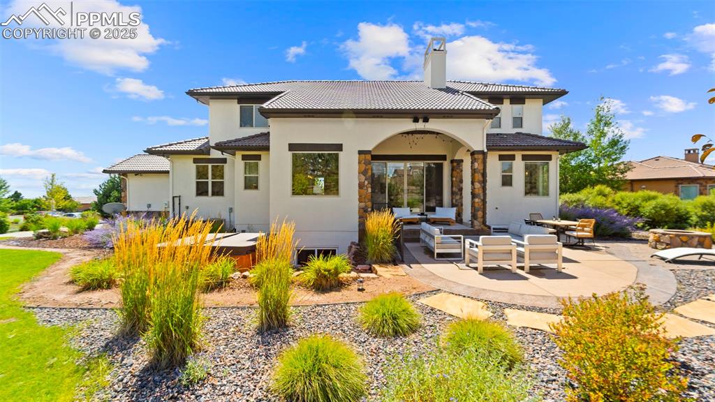 Image 41 of 50: Back of property featuring a patio, outdoor lounge area, a chimney, stucco 