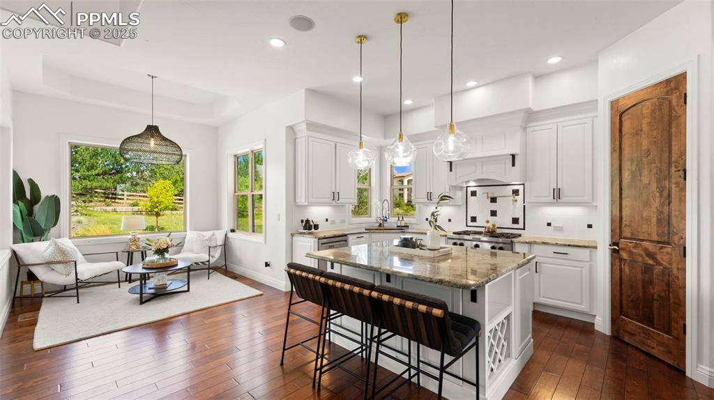 Image 9 of 50: Kitchen featuring white cabinets, light stone countertops, a breakfast bar 