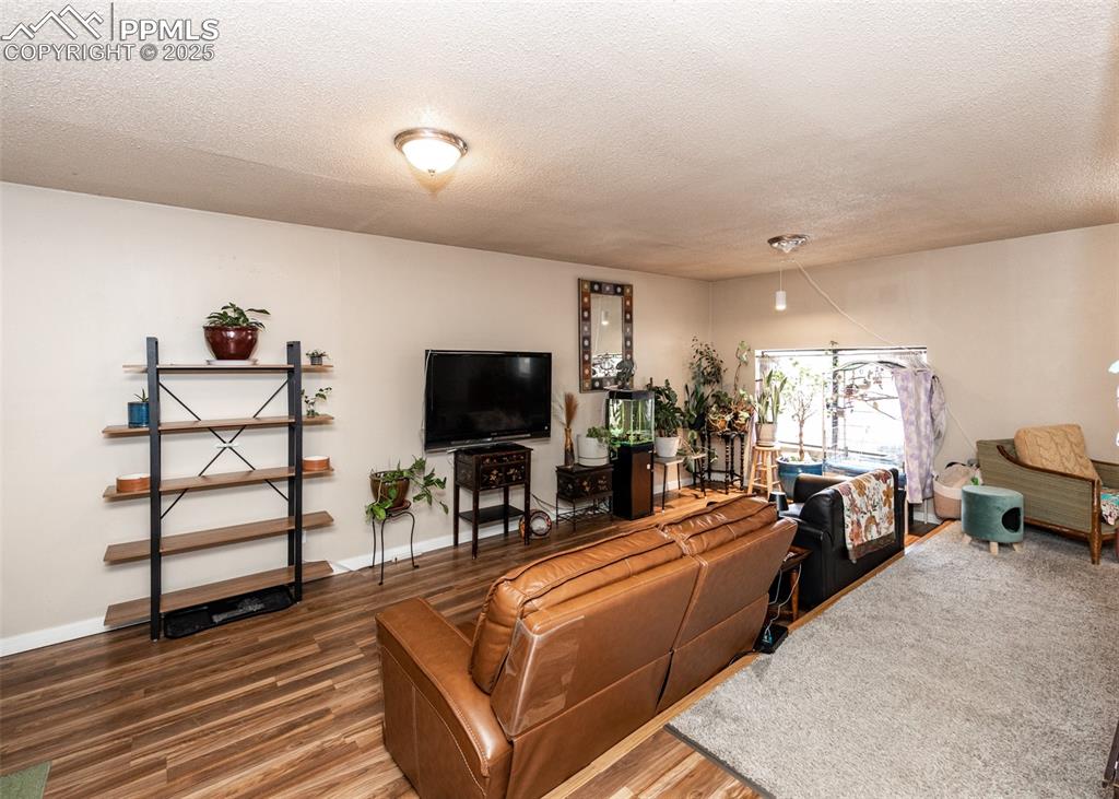 Image 13 of 42: Living area with a textured ceiling, wood finished floors, and baseboards