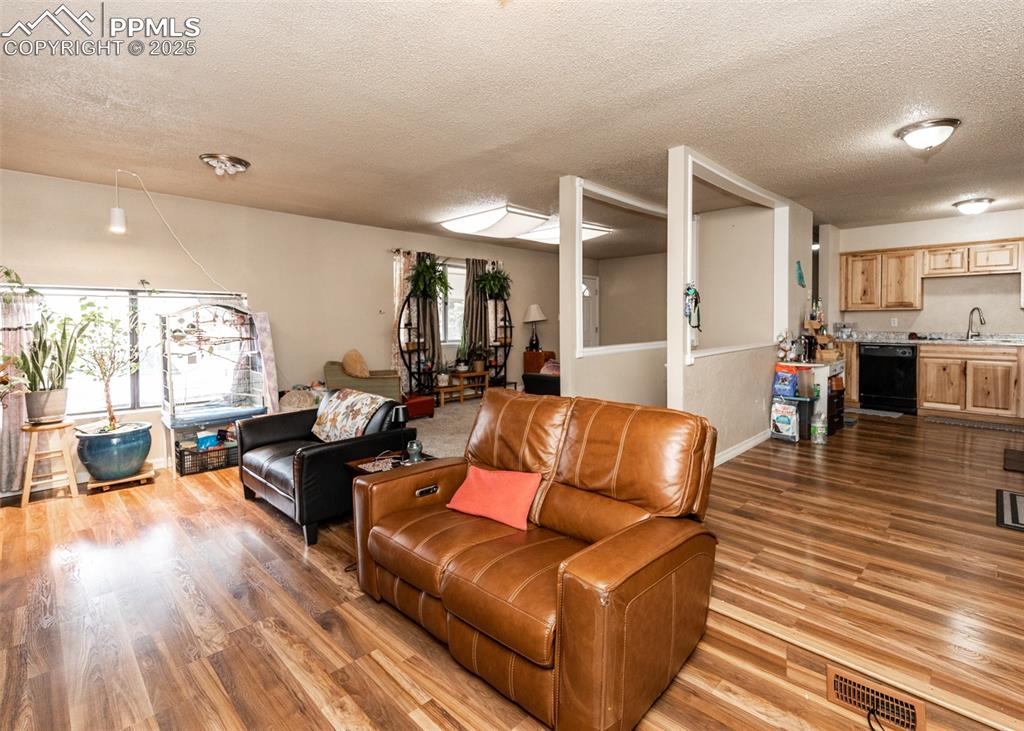 Image 15 of 42: Living area with a textured ceiling, wood finished floors, and baseboards