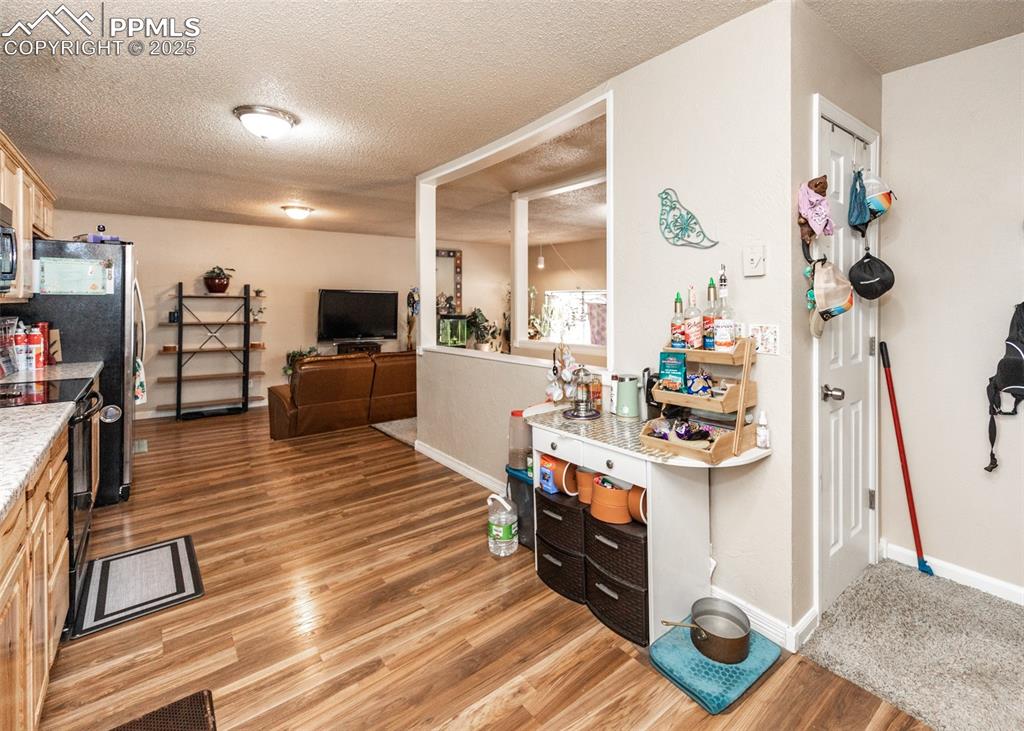 Image 16 of 42: Kitchen with a textured ceiling, light countertops, black appliances, light