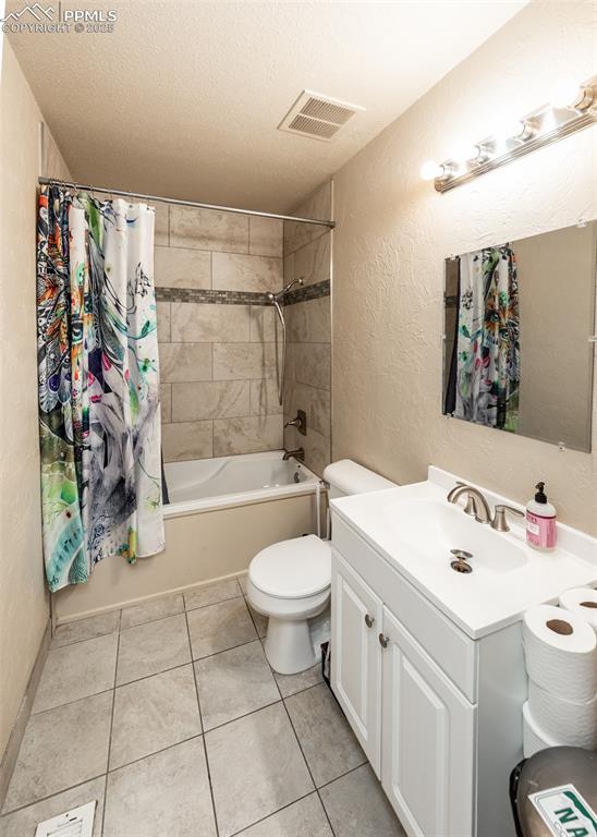 Image 24 of 42: Bathroom with toilet, shower / bath combo with shower curtain, a textured w