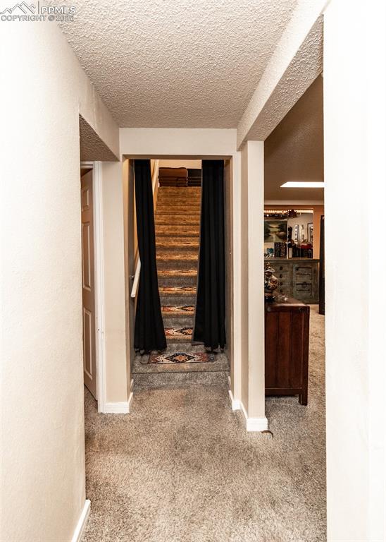 Image 31 of 42: Corridor featuring carpet, a textured ceiling, and baseboards