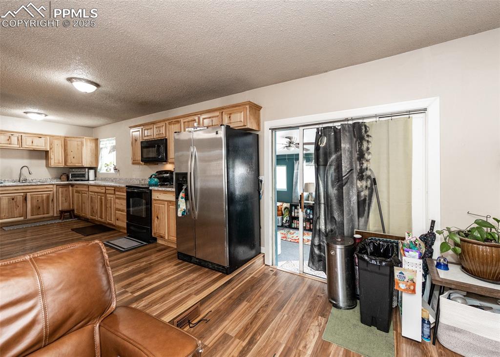 Image 7 of 42: Kitchen featuring black appliances, light countertops, dark wood-type floor