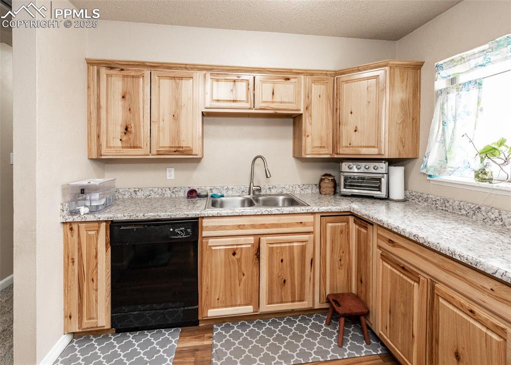 Image 9 of 42: Kitchen featuring dishwasher, a sink, light countertops, dark wood-style fl