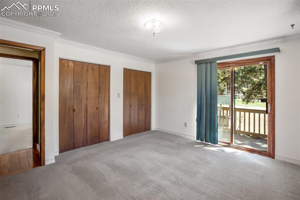 Image 10 of 36: Unfurnished bedroom with carpet floors, a textured ceiling, and access to o