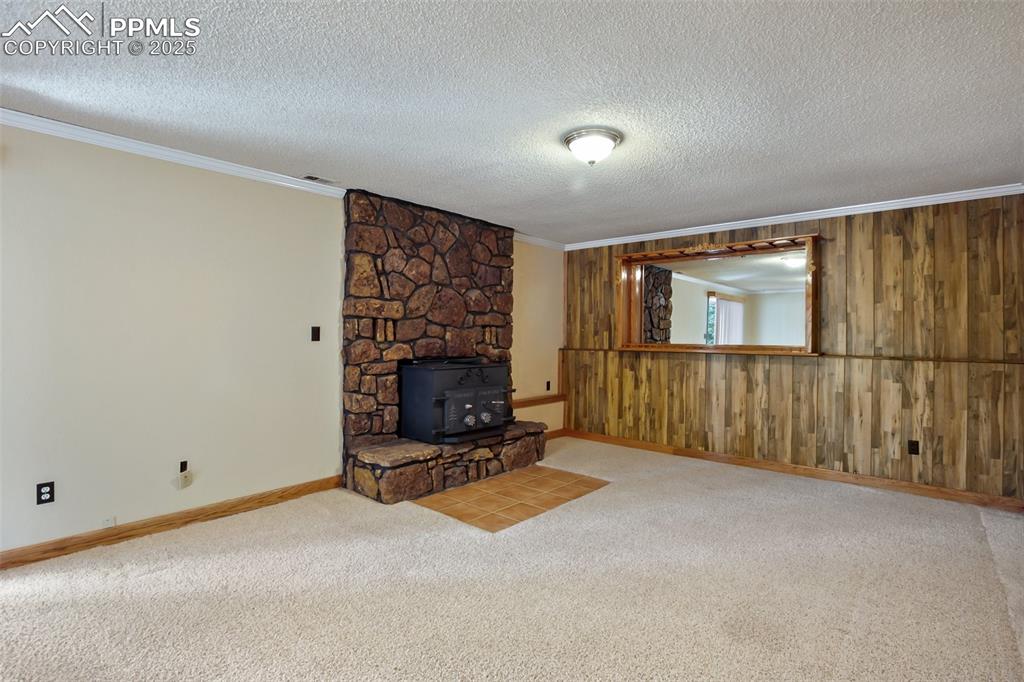 Image 20 of 36: Lower level family room with wood stove