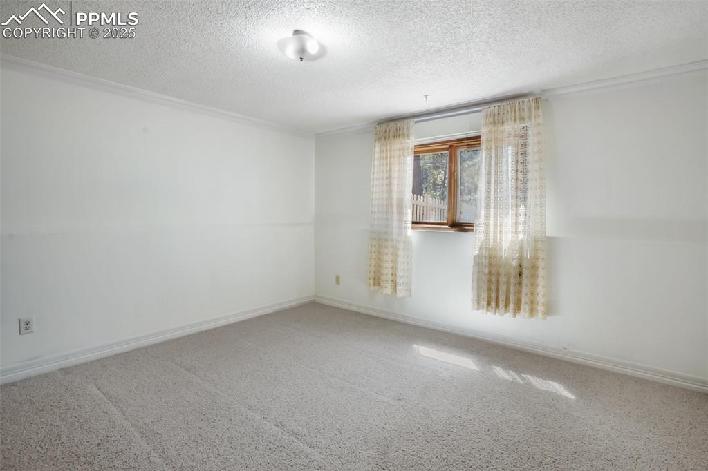 Image 21 of 36: Lower Level Bedroom #3Carpeted spare room featuring baseboards and a textur