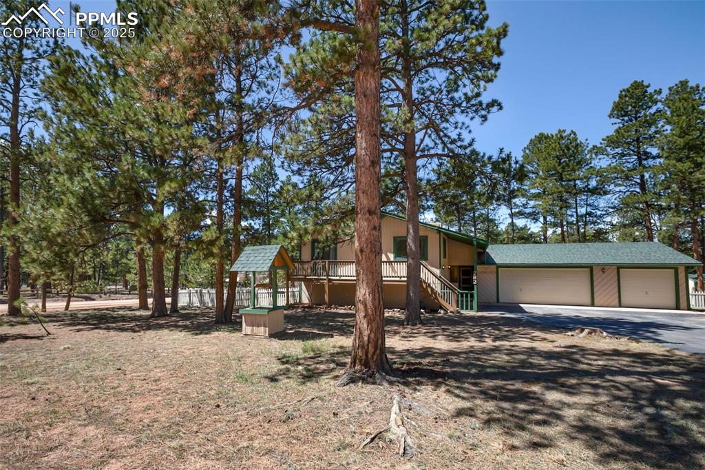 Image 34 of 36: View of front facade with an attached garage, stairway, and dirt driveway