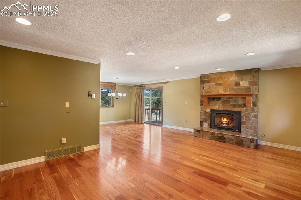 Image 4 of 36: Unfurnished living room with a textured ceiling, visible vents, light wood-