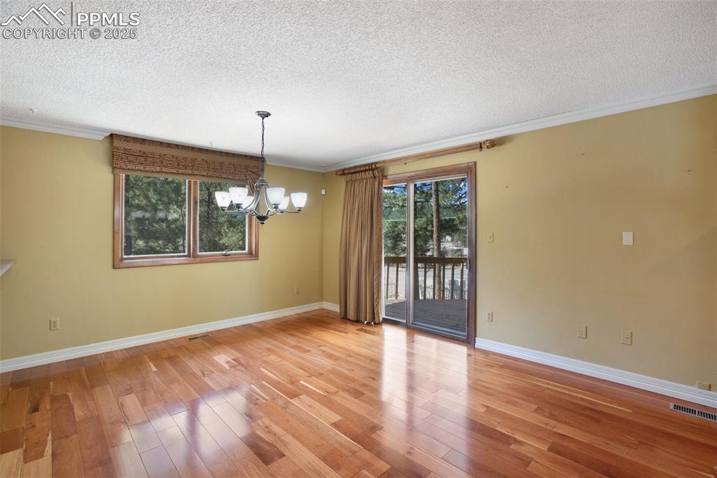Image 5 of 36: Unfurnished room with an inviting chandelier, a textured ceiling, and visib