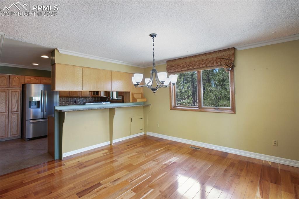 Image 7 of 36: Kitchen featuring a textured ceiling, light wood-style floors, stainless st
