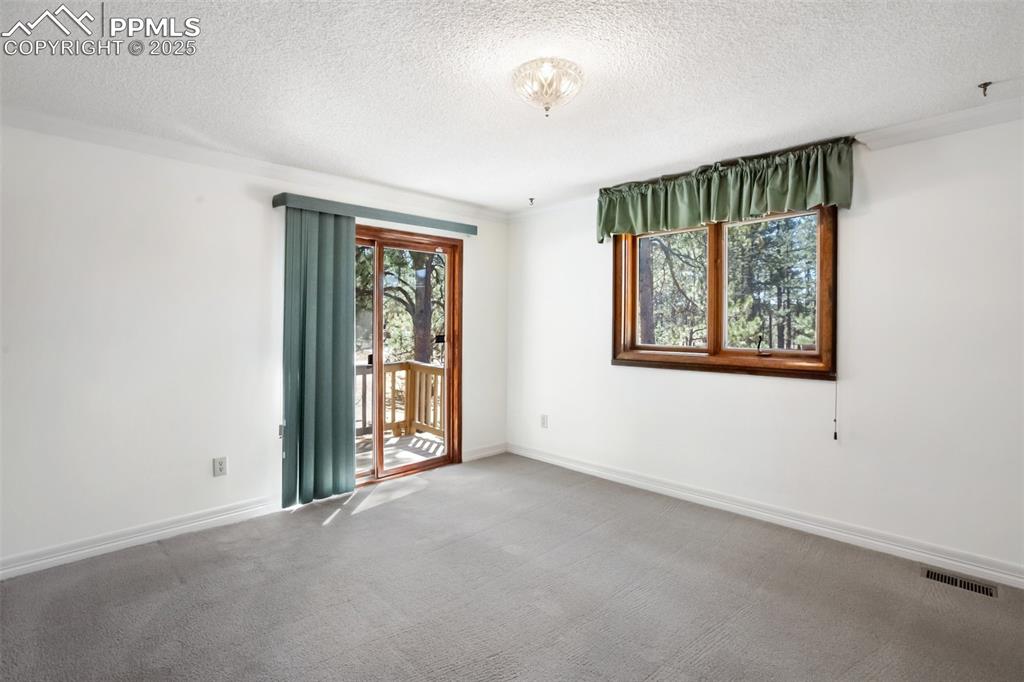 Image 9 of 36: Carpeted spare room featuring a textured ceiling, visible vents, and basebo