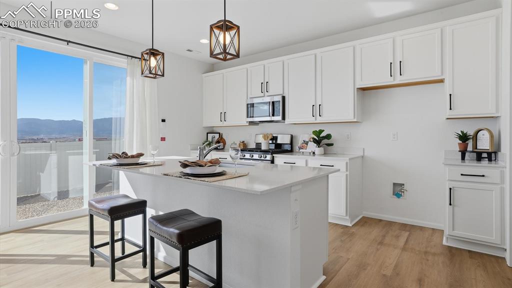 Image 15 of 45: Island Kitchen with breakfast bar, pendant lights, and white cabinets with