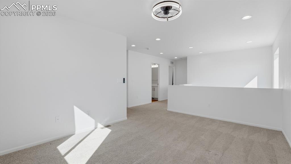 Image 23 of 45: Spacious upper level Loft with ceiling fan and neutral carpet.