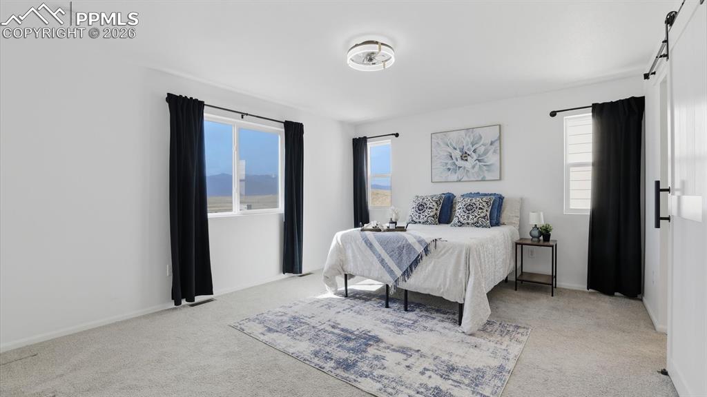 Image 27 of 45: The upper level Primary Retreat has a ceiling fan, neutral carpet, and wind