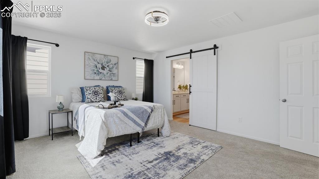 Image 28 of 45: The upper level Primary Bedroom has a barn door into the spa-like Shower Ba