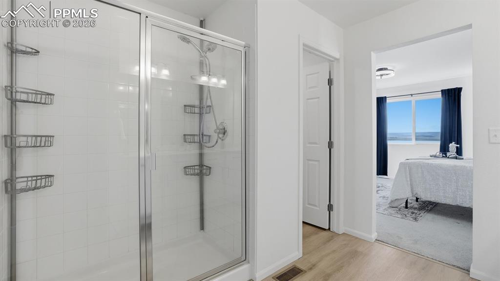 Image 32 of 45: Enclosed shower in the Primary Bathroom with view into the Primary Bedroom.