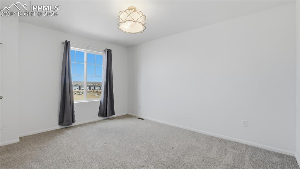 Image 36 of 45: Upper Level Bedroom #3 with neutral carpet, walk in closet, and view window