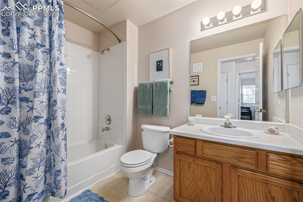 Image 14 of 22: Secondary Bath with shower / tub combo, vanity, and light tile patterned fl