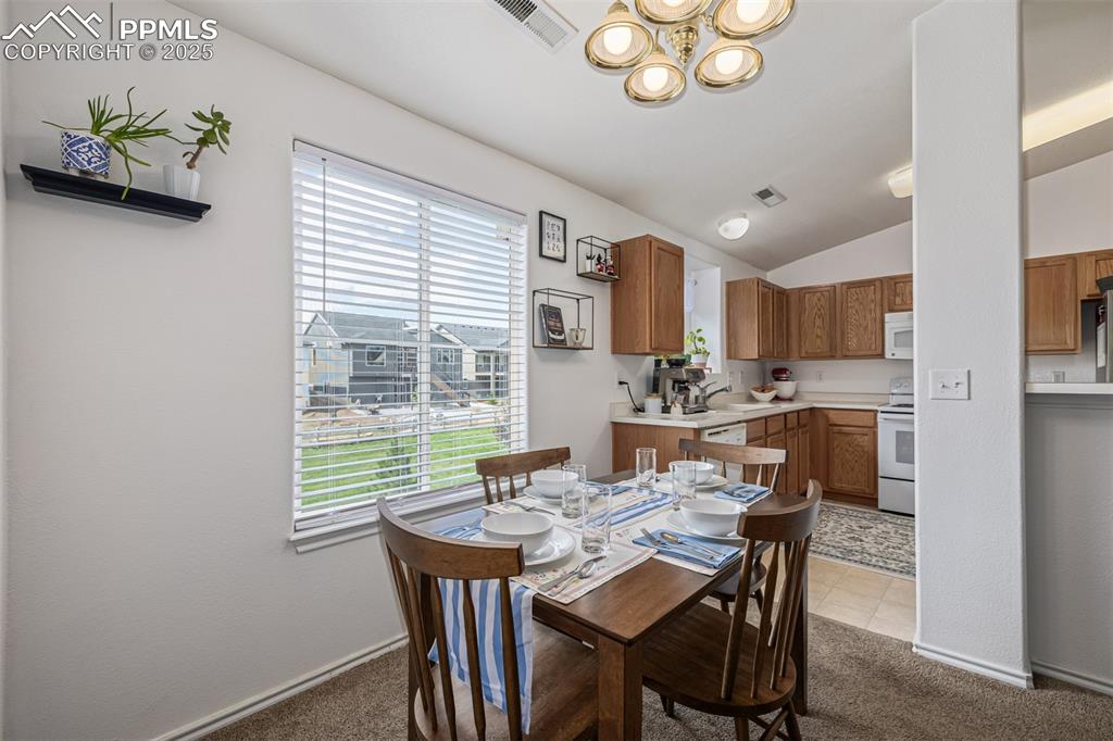 Image 5 of 22: Dining room featuring light colored carpet, lofted ceiling, and light tile 