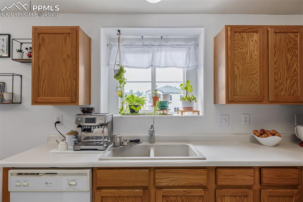 Image 8 of 22: Kitchen featuring light countertops, dishwasher, and brown cabinetry