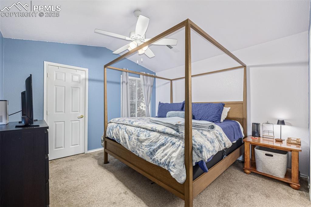 Image 9 of 22: Bedroom featuring light colored carpet, vaulted ceiling, and walk in closet