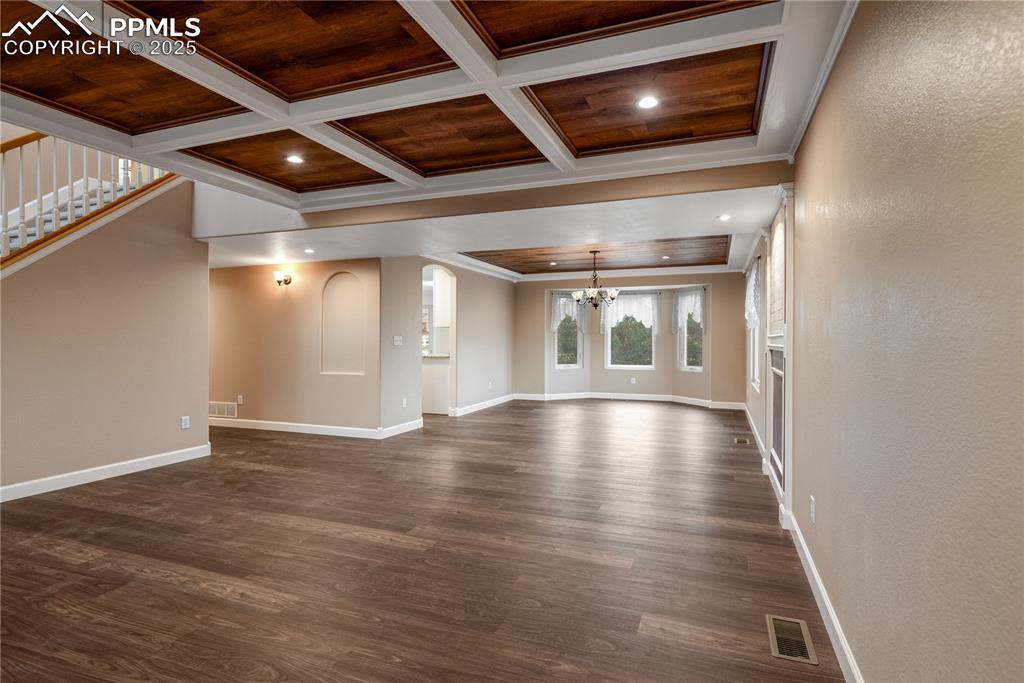 Image 10 of 46: Unfurnished living room featuring a chandelier, dark wood-type flooring, cr