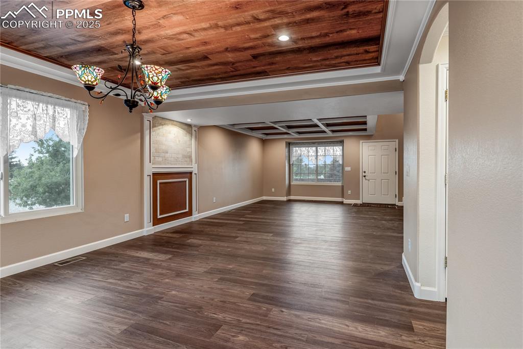 Image 12 of 46: Unfurnished room featuring wood ceiling, dark wood-style flooring, a chande