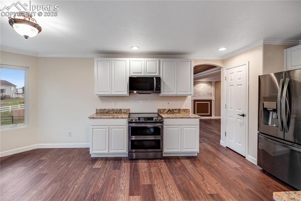 Image 14 of 46: Kitchen with stainless steel appliances, arched walkways, ornamental moldin