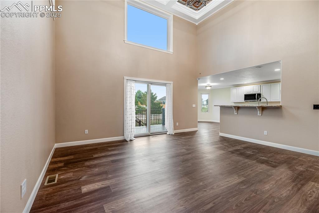 Image 19 of 46: Unfurnished living room with dark wood-style floors and a towering ceiling