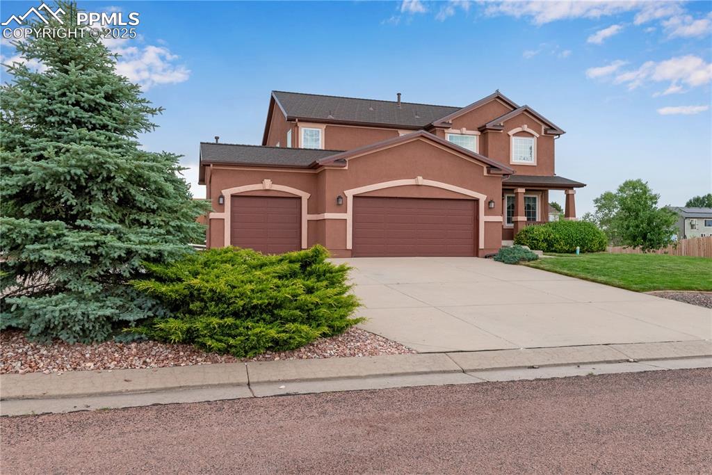 Image 2 of 46: View of front of property featuring stucco siding, an attached garage, driv