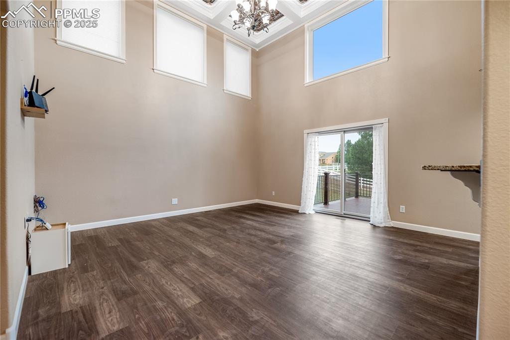 Image 23 of 46: Spare room featuring a chandelier, dark wood-type flooring, a high ceiling,