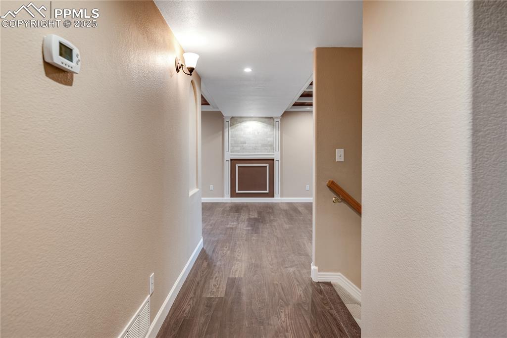 Image 25 of 46: Hallway with dark wood-style floors, a textured wall, and recessed lighting